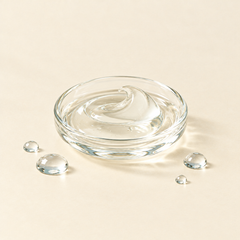 A glass dish of clear, silky serum with a few droplets